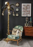 Détail du salon avec un fauteuil rétro Ercol, un lampadaire palmier et un buffet vintage en bois.
