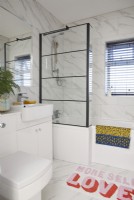 Salle de bain avec carrelage en marbre et pare-douche en cristal.