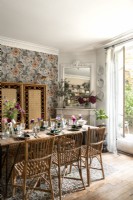 Salle à manger éclectique avec meubles en osier et papier peint floral