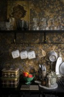 Détail du plan de travail de cuisine noir avec mur tapissé en relief doré