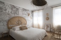 Chambre de campagne moderne avec mur de plâtre nu et tête de lit en rotin