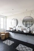 Lavabos jumeaux dans une salle de bains monochrome contemporaine avec mur en marbre