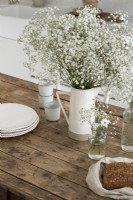 Fleurs blanches et verseuse sur table de cuisine en bois de campagne