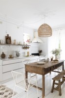 Cuisine-salle à manger de campagne blanche avec grande table et banc en bois