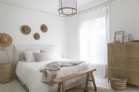 Chambre peinte en blanc avec des meubles en bois et en rotin