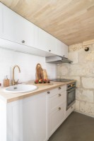 Petite cuisine moderne avec mur en pierres apparentes et plafond en bois