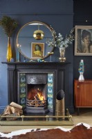 Salon avec cheminée noire, miroir rond, œuvres d'art rétro et murs peints en bleu marine.