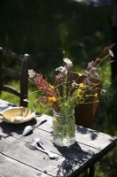 Arrangement de fleurs sauvages dans un vieux bocal en verre sur table de jardin