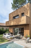 Espace de vie extérieur sur terrasse en bois à côté de la piscine et de la maison moderne