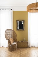 Chaise en osier à côté d'un mur peint en moutarde dans la chambre