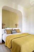Mur jaune dans une alcôve voûtée autour de la tête de lit