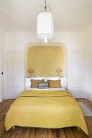 Alcôve peinte en jaune autour de la tête de lit avec literie jaune