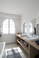Miroirs arqués sur deux lavabos dans la salle de bain avec fenêtres cintrées