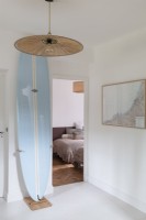 Planche de surf calée dans un couloir peint en blanc