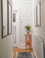 Couloir avec mur de confettis washi, œuvres d'art encadrées et table de plantes roses.