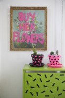 Détail du hall d'entrée avec imprimé 'Buy her flowers', pots de plantes décorés de washi tape et placard.