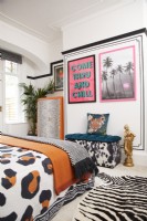 Chambre à coucher avec un effet de faux lambris noir (avec du ruban washi noir), des œuvres d'art encadrées, une literie à imprimé animal, un tapis et un siège de rangement.