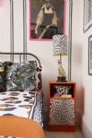 Détail de la chambre avec un effet de faux lambris noir (avec du ruban washi noir), des œuvres d'art encadrées, une literie à imprimé animal et une table de chevet orange recyclée.