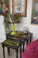 Détail de salon coloré avec un nid de tables d'appoint, une lampe de table jungle et un mur de galerie.