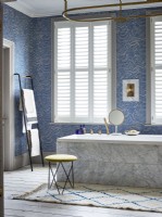 Salle de bain luxueuse avec baignoire en marbre et volets blancs
