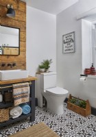 Salle de bain avec boiseries derrière les doubles vasques, meuble de rangement avec porte-serviettes et tommettes au sol.
