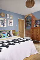 Chambre avec briques apparentes d'origine, murs peints en bleu et mobilier rétro.