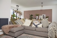 Coin salon dans un espace décloisonné avec un canapé confortable et un blocage de couleur rose sur le mur.