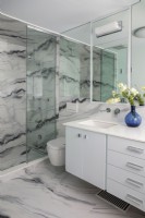 Salle de bains blanche moderne avec sol et murs à motifs en marbre.