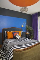 Formes bauhaus peintes audacieuses et colorées dans une chambre contemporaine. Avec une tête de lit antique, des tissus d'ameublement à motifs et des rideaux de velours violet.