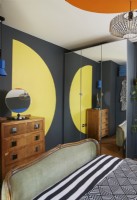 Formes bauhaus peintes audacieuses et colorées dans une chambre contemporaine. Montrant un demi-cercle jaune, une commode vintage et une armoire à glace.