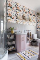 Meuble-lavabo rose dans une salle de bains carrelée et tapissée de gris