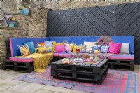Terrasse de divertissement en plein air avec des palettes en bois peintes transformées en sièges et en table
