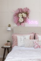 Détail de lit et table de chevet contre un mur lambrissé dans la chambre d'une adolescente