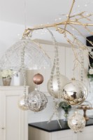 Boules de Noël suspendues à une brindille dorée entre des suspensions dans une cuisine-salle à manger ouverte