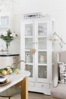 Grande armoire peinte à la main blanche récupérée avec portes vitrées dans une cuisine-salle à manger ouverte