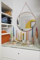 Détail de la chambre montrant des bougies, un miroir, un espace de rangement ouvert pour les vêtements et les tiroirs.