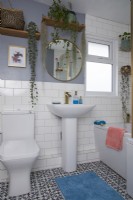 Salle de bain avec carrelage blanc, murs gris, sol à motifs et étagères ouvertes.