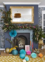 Salon de Noël avec un sapin décoré et de la verdure sur la cheminée.