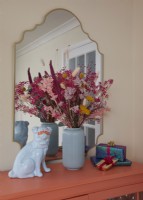 Détail du salon montrant une armoire recyclée avec un vase de fleurs séchées et un ornement de chien.