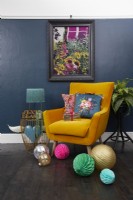 Salon avec un mur peint en bleu foncé, une chaise jaune de style milieu du siècle, des œuvres d'art et des décorations de Noël.