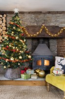 Maison de campagne salon avec arbre de Noël et poêle à bois dans un cantou en pierre et brique