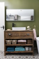 Meuble-lavabo en bois fait main sur mesure avec lavabo de salle de bain blanc contre un mur vert
