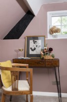 Détail d'un bureau et d'une chaise en bois dans une chambre mansardée rose