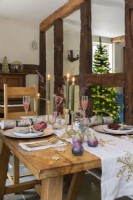Coin repas avec table à manger en bois dressée pour Noël devant poutres apparentes