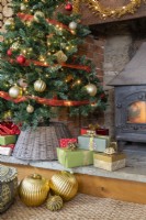 Détail de cadeaux et de boules sous un sapin de Noël près d'un poêle à bois
