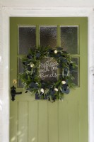 Couronne de Noël sur une porte d'entrée vitrée de cottage vert