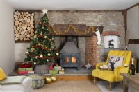 Maison de campagne salon avec arbre de Noël et poêle à bois et bûche dans un cantou en pierre et brique