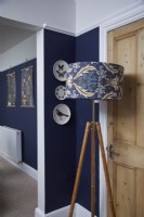 Détail du salon montrant un lampadaire à motifs, avec des murs peints en bleu foncé.