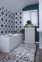 Salle de bain avec carreaux à motifs, murs peints en bleu et ensemble de tiroirs vintage.