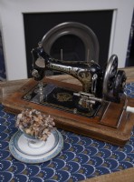 Détail montrant une machine à coudre vintage avec une cheminée en arrière-plan.
